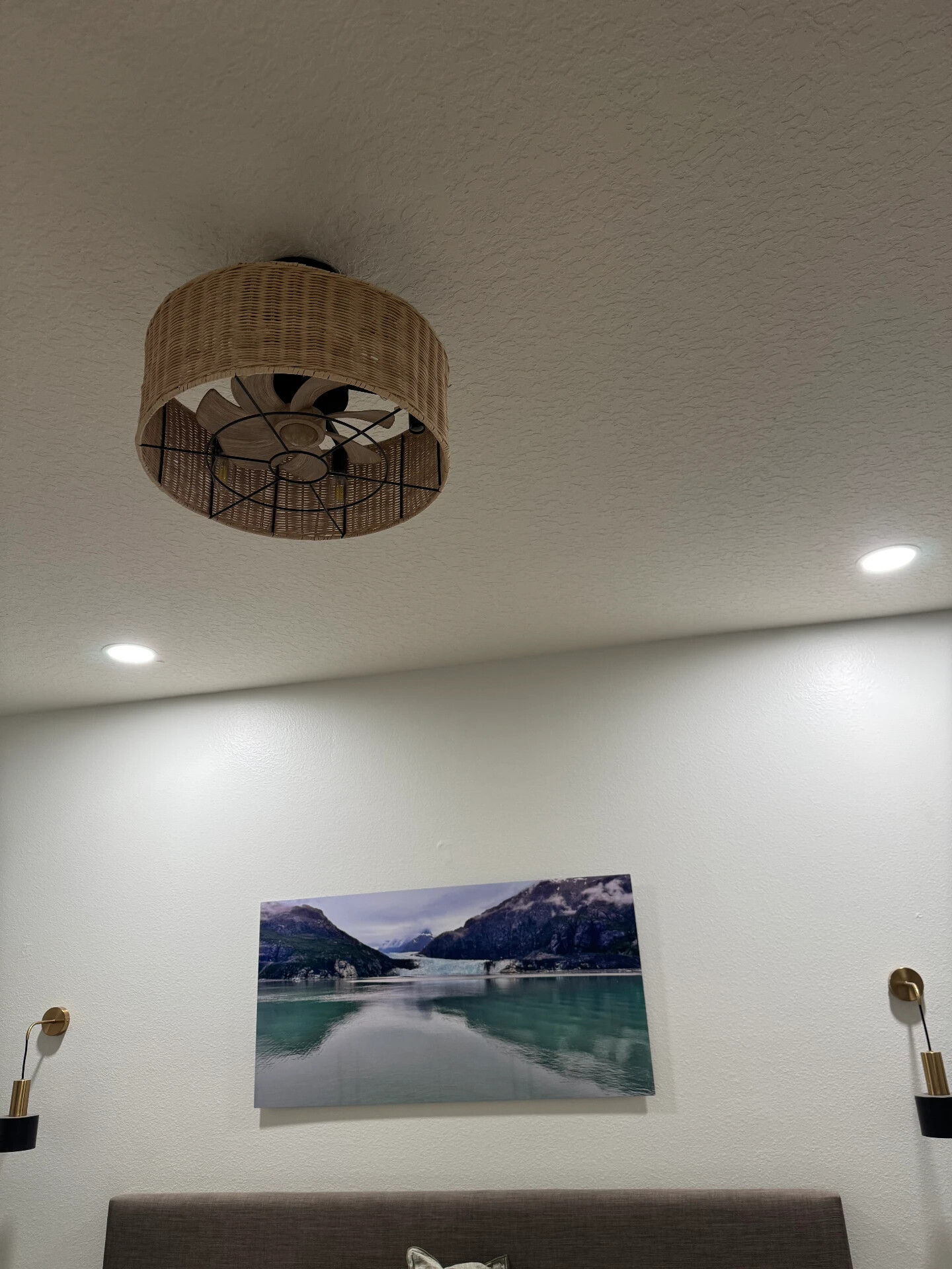 Bedroom with woven ceiling fan, recessed can lights, and wall sconces